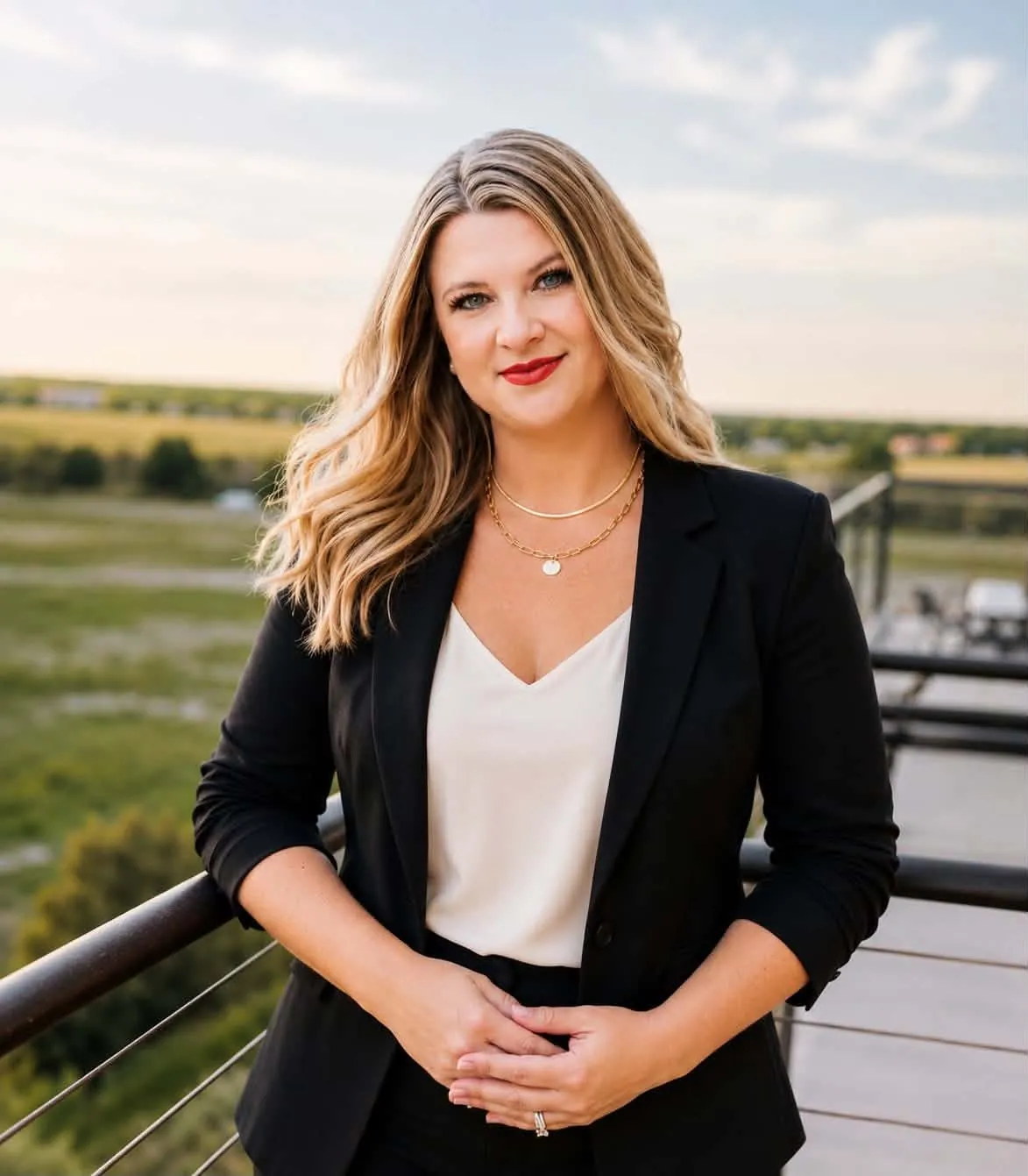 Ashley Heckathorn, Compass Broker Associate and Johnstown Colorado Realtor, in a black blazer at golden hour with the Colorado prairie behind her